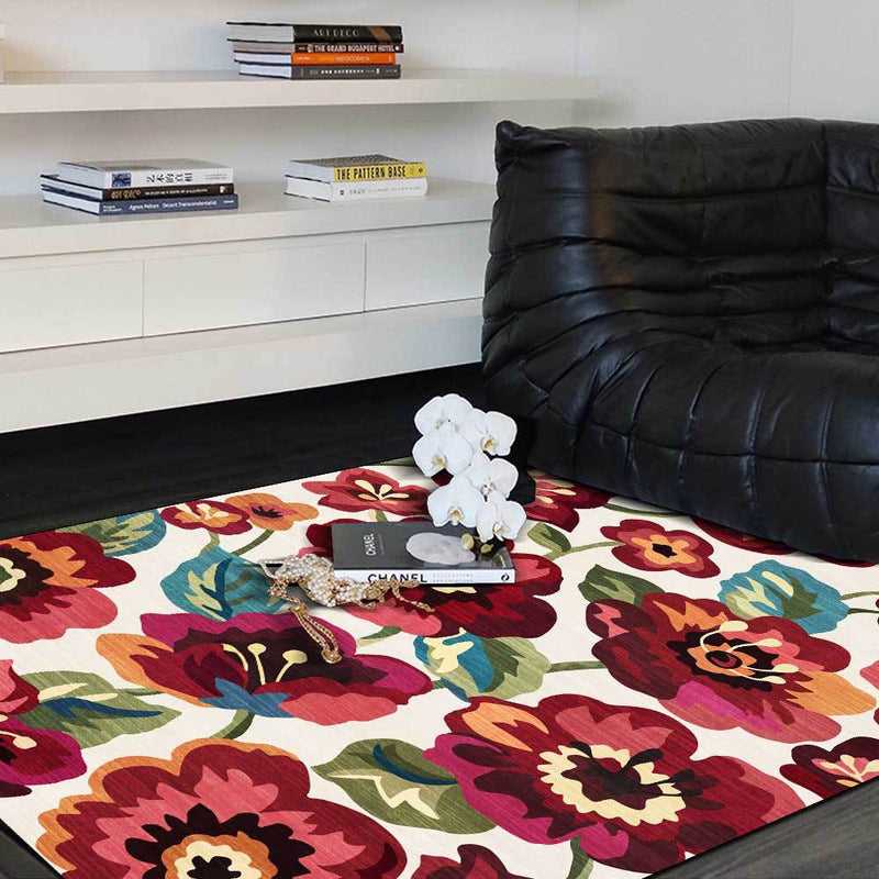 Colorful floral-patterned living room rug with vibrant red, pink, and orange flowers on a white background.