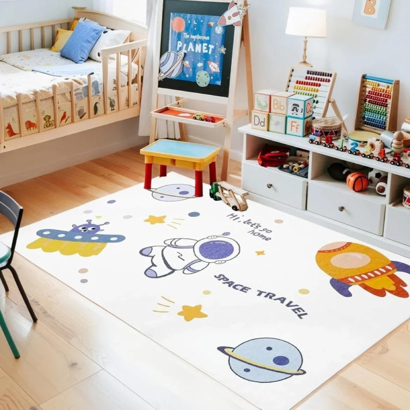 Kids rug with outer space theme featuring cartoon astronaut, rocket, UFO, planets, stars, and the phrases 'Hi, let's go home' and 'SPACE TRAVEL'.