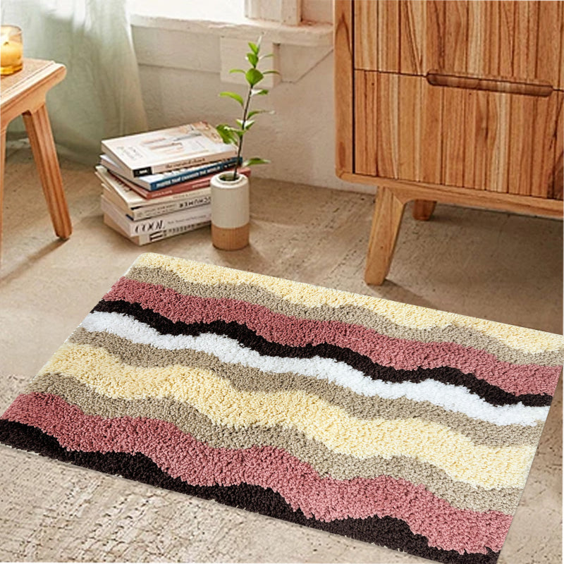 Rectangular bathroom rug with a wavy stripe pattern in pink, yellow, beige, brown, and white, featuring a soft and plush texture.