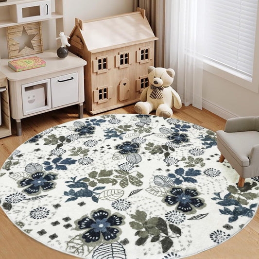 Round living room rug with blue and green floral pattern on an ivory background, placed in a cozy wooden interior with a rocking horse and storage cabinet.