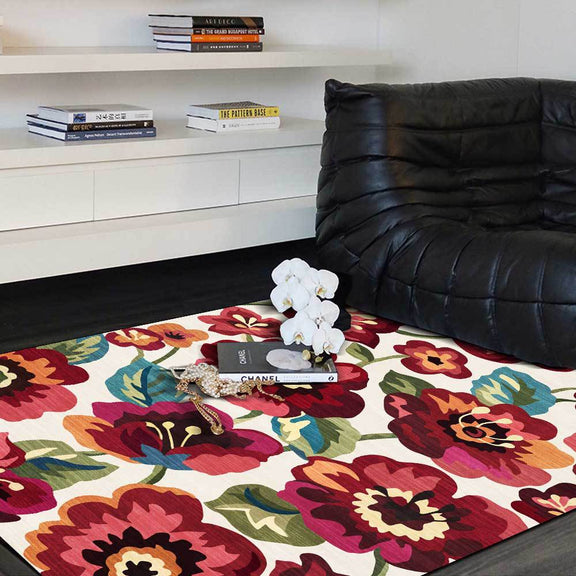 Colorful floral-patterned living room rug with vibrant red, pink, and orange flowers on a white background.