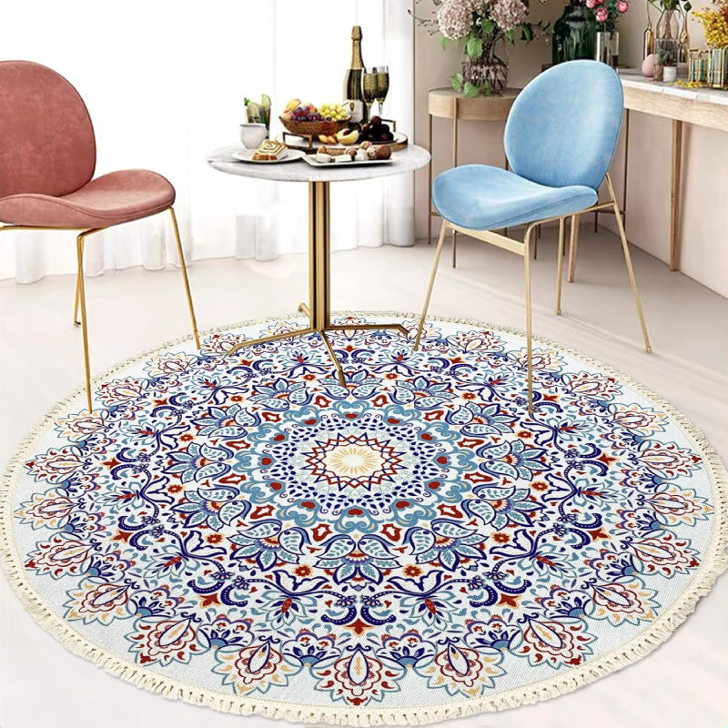 Round bohemian-style rug with an intricate mandala pattern in blue, terracotta, and gold, featuring floral and geometric motifs and finished with fringe tassels around the edge.