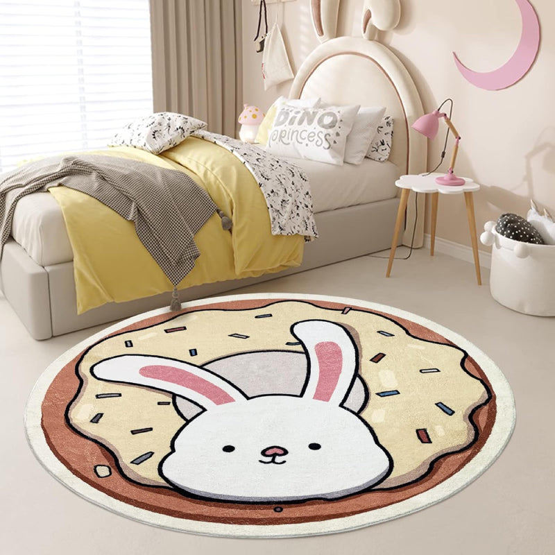 A round children's rug featuring a cute white bunny with pink ears popping out of a donut topped with cream-colored frosting and colorful sprinkles.
