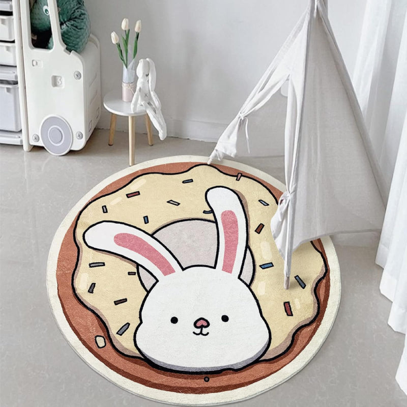 A round children's rug featuring a cute white bunny with pink ears popping out of a donut topped with cream-colored frosting and colorful sprinkles.