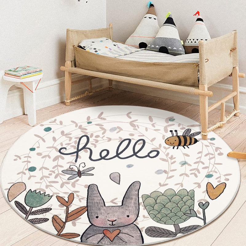 Round children's rug featuring a cute gray Easter bunny holding a heart, surrounded by flowers, a bee, a butterfly, and the word "hello" in playful script on a light background.