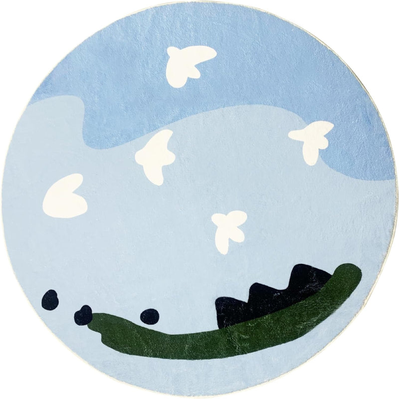 Round kids rug featuring a whimsical sky scene with light blue and dark blue abstract clouds, white cartoon-style birds flying, and green and black land-like shapes at the bottom on a soft background.