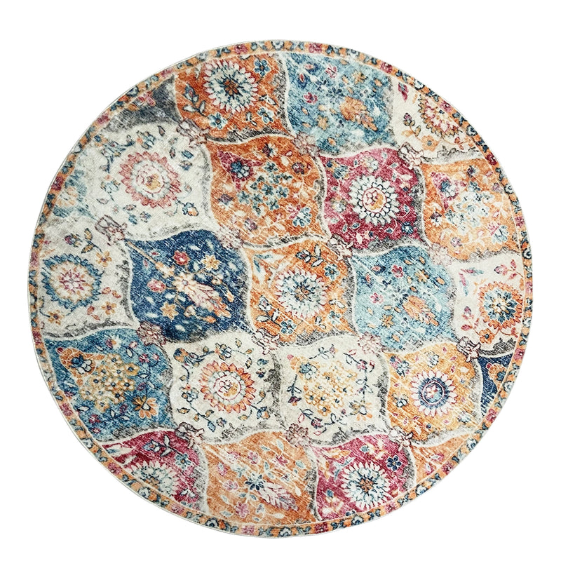 Round boho vintage area rug with a colorful patchwork of floral and medallion patterns in orange, blue, red, and cream tones.