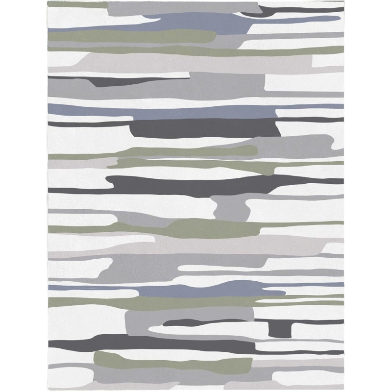 Modern living room with a neutral-tone multicolor block area rug featuring abstract horizontal stripes in gray, white, green, and black tones, placed on a wooden floor with cozy furniture and minimalist decor.