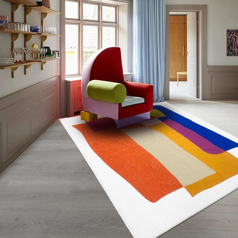 Abstract living room rug with overlapping geometric shapes in vibrant colors including orange, blue, yellow, magenta, and cream.