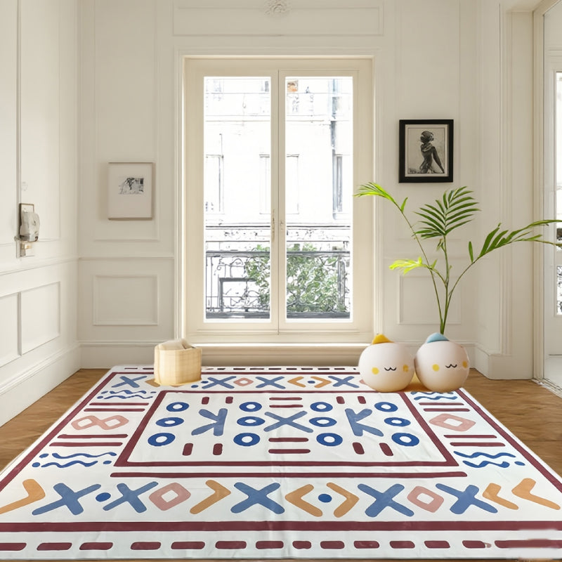 Geometric tribal-style rug with bold symbolic patterns laid in a bright, elegant living room setting.