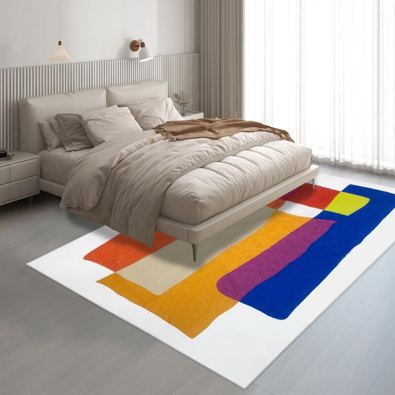 Abstract living room rug with overlapping geometric shapes in vibrant colors including orange, blue, yellow, magenta, and cream.