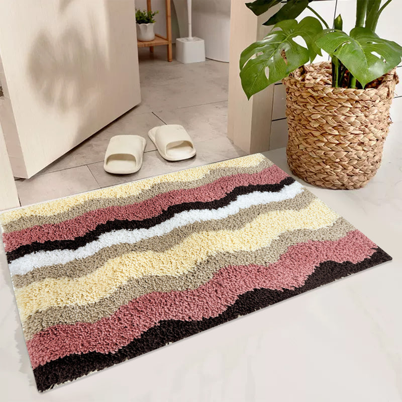Rectangular bathroom rug with a wavy stripe pattern in pink, yellow, beige, brown, and white, featuring a soft and plush texture.