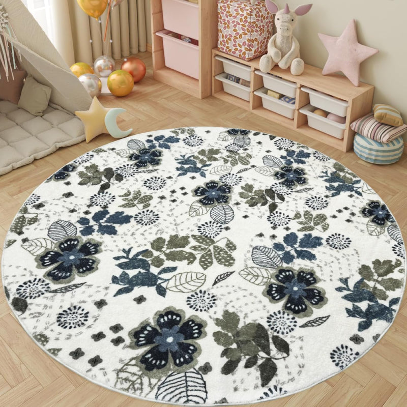 Round living room rug with blue and green floral pattern on an ivory background, placed in a cozy wooden interior with a rocking horse and storage cabinet.