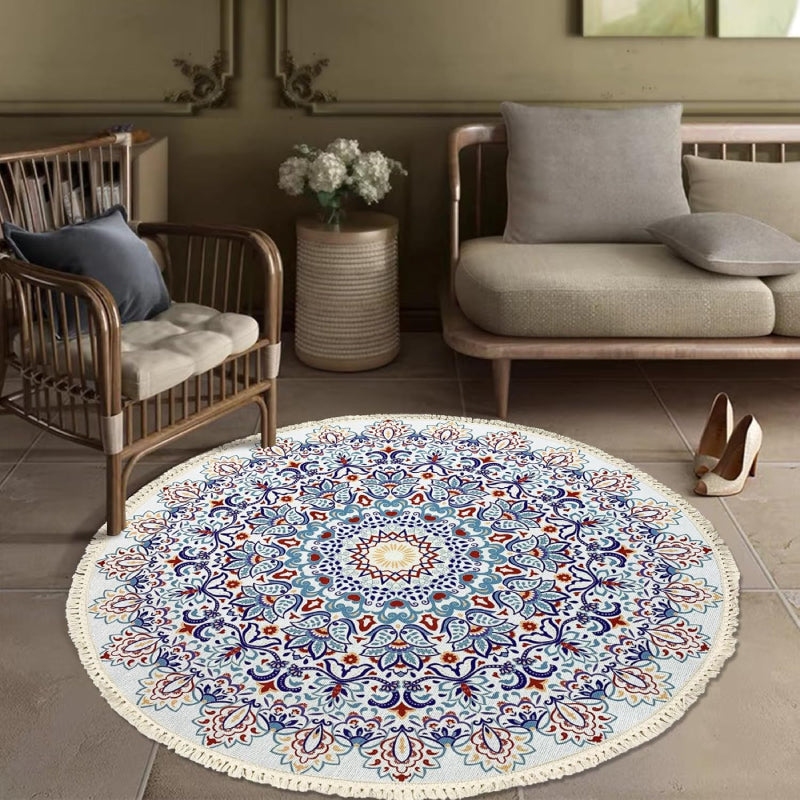 Round bohemian-style rug with an intricate mandala pattern in blue, terracotta, and gold, featuring floral and geometric motifs and finished with fringe tassels around the edge.