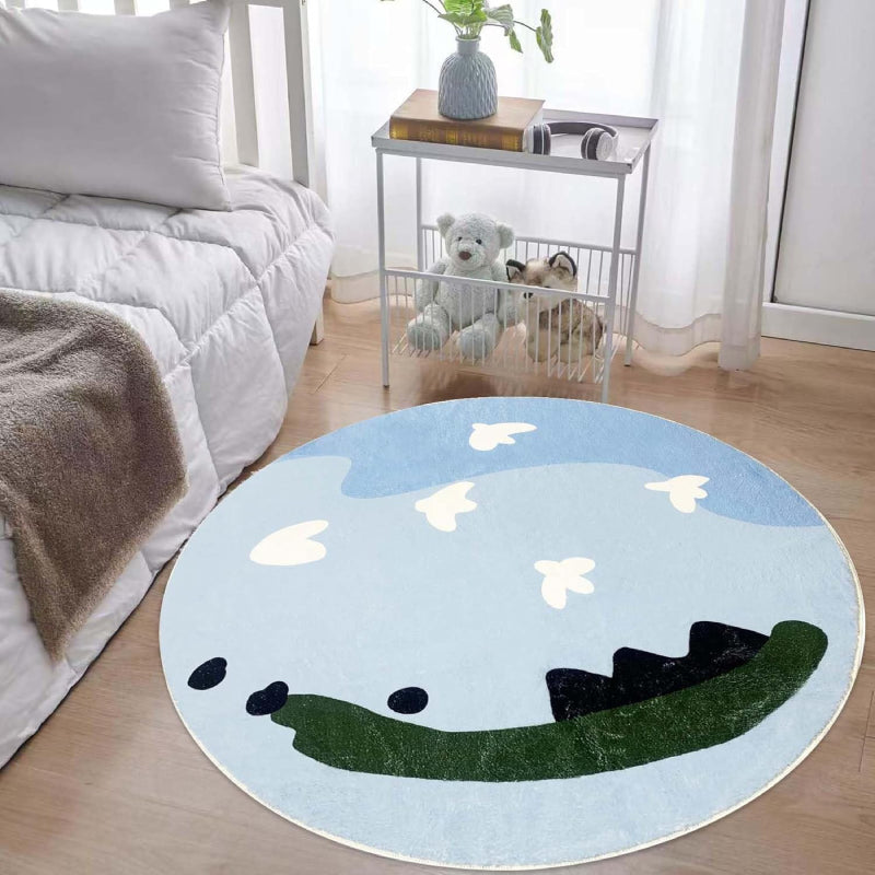 Round kids rug featuring a whimsical sky scene with light blue and dark blue abstract clouds, white cartoon-style birds flying, and green and black land-like shapes at the bottom on a soft background.