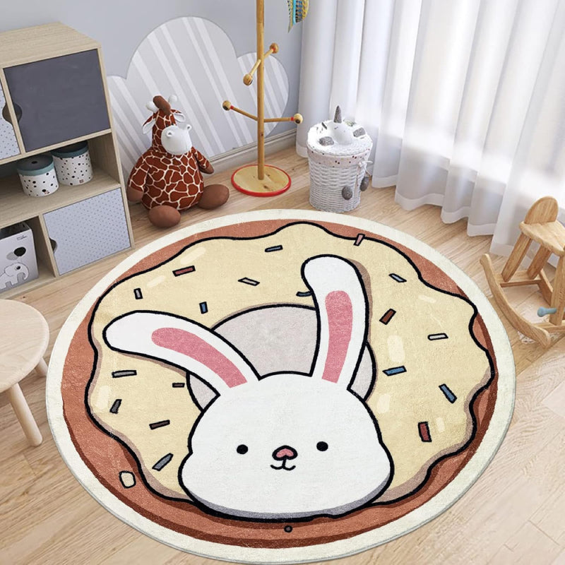 A round children's rug featuring a cute white bunny with pink ears popping out of a donut topped with cream-colored frosting and colorful sprinkles.