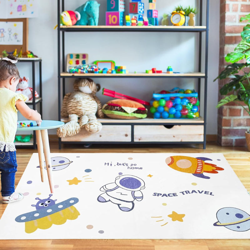Kids rug with outer space theme featuring cartoon astronaut, rocket, UFO, planets, stars, and the phrases 'Hi, let's go home' and 'SPACE TRAVEL'.
